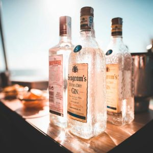 Chilled bottles of gin and vodka on a sunlit outdoor table, ideal for a summer celebration.